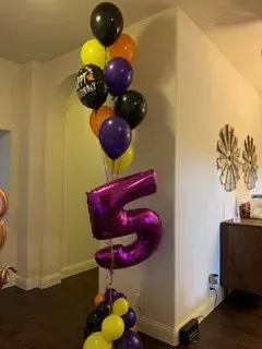 A bunch of balloons with a purple number 5 on top of them.
