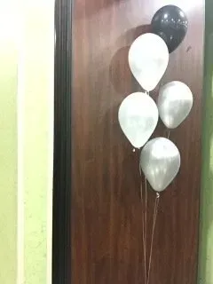 A bunch of balloons are sitting on a wooden door.