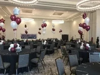 A large room filled with tables and chairs and balloons.