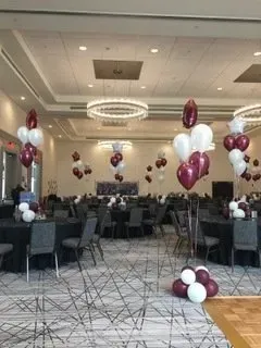 A large room filled with tables and chairs and balloons.