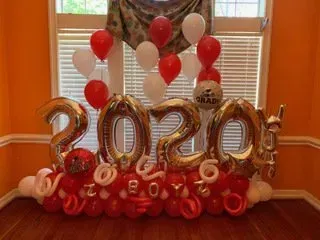 A bunch of balloons are sitting in a room in front of a window.