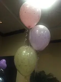 Three balloons are hanging from the ceiling in a room.
