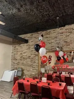 A room with tables and chairs and balloons hanging from the ceiling.
