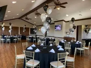A large room filled with tables and chairs and balloons.