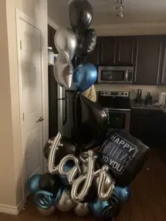 A bunch of balloons are sitting on the floor in a kitchen.