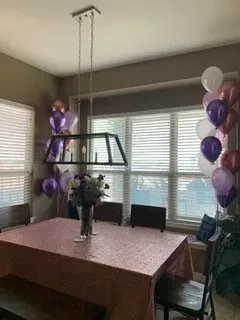 A dining room table with balloons and flowers on it.