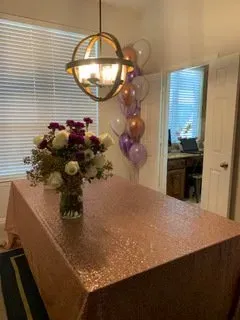 A table with a rose gold tablecloth and a vase of flowers on it.