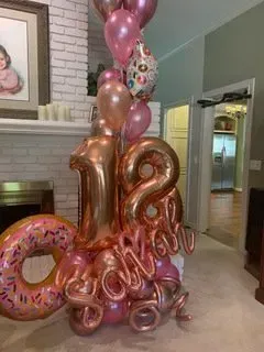 A bunch of balloons are sitting on top of a donut in a living room.