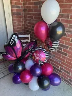 A bunch of balloons are sitting on a porch in front of a brick wall.