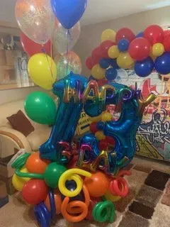 A bunch of balloons are sitting on the floor in a living room.
