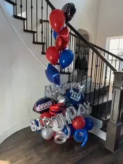 A bunch of balloons are sitting on the floor next to a staircase.