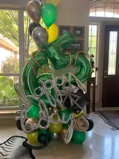 A bunch of green and gold balloons in a living room.