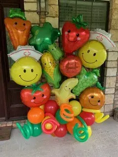 A bunch of balloons in the shape of fruits and vegetables