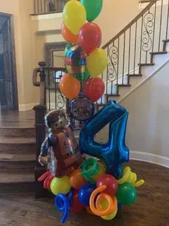 A bunch of balloons are sitting on the floor in front of a staircase.