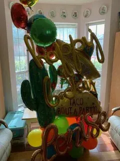 A bunch of balloons are sitting on a table in a living room.