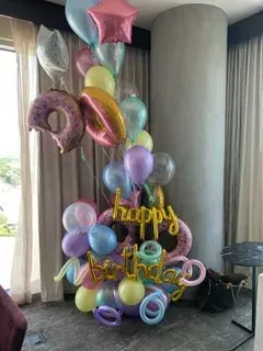 A bunch of balloons are sitting in a room next to a window.