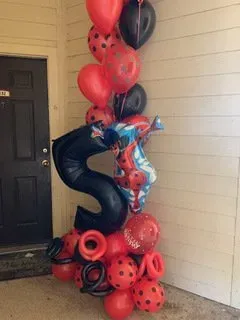 A bunch of red and black balloons are stacked on top of each other in front of a door.