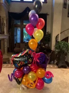 A bunch of balloons are sitting on a table in a living room.
