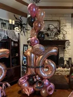 A bunch of balloons are sitting on a table in a living room.