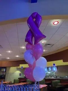 A bunch of pink and white balloons are sitting on a table in a restaurant.