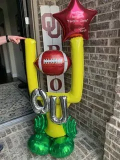 A person is pointing at a football goal post made of balloons.