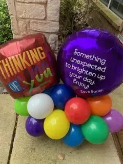 A bunch of balloons with one that says `` something unexpected to brighten up your day enjoy ''