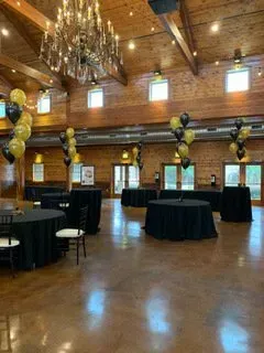 A large room with tables and chairs and balloons hanging from the ceiling.