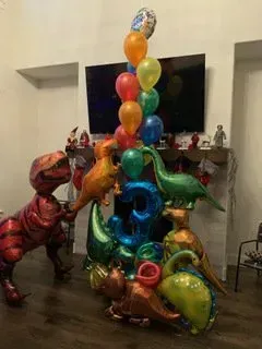 A bunch of dinosaur balloons are stacked on top of each other in a living room.
