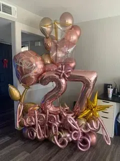 A wall covered in balloons and a neon sign that says `` twenty one ''.