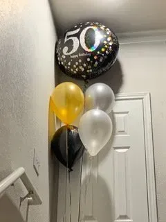 A bunch of balloons are hanging on a wall next to a door.
