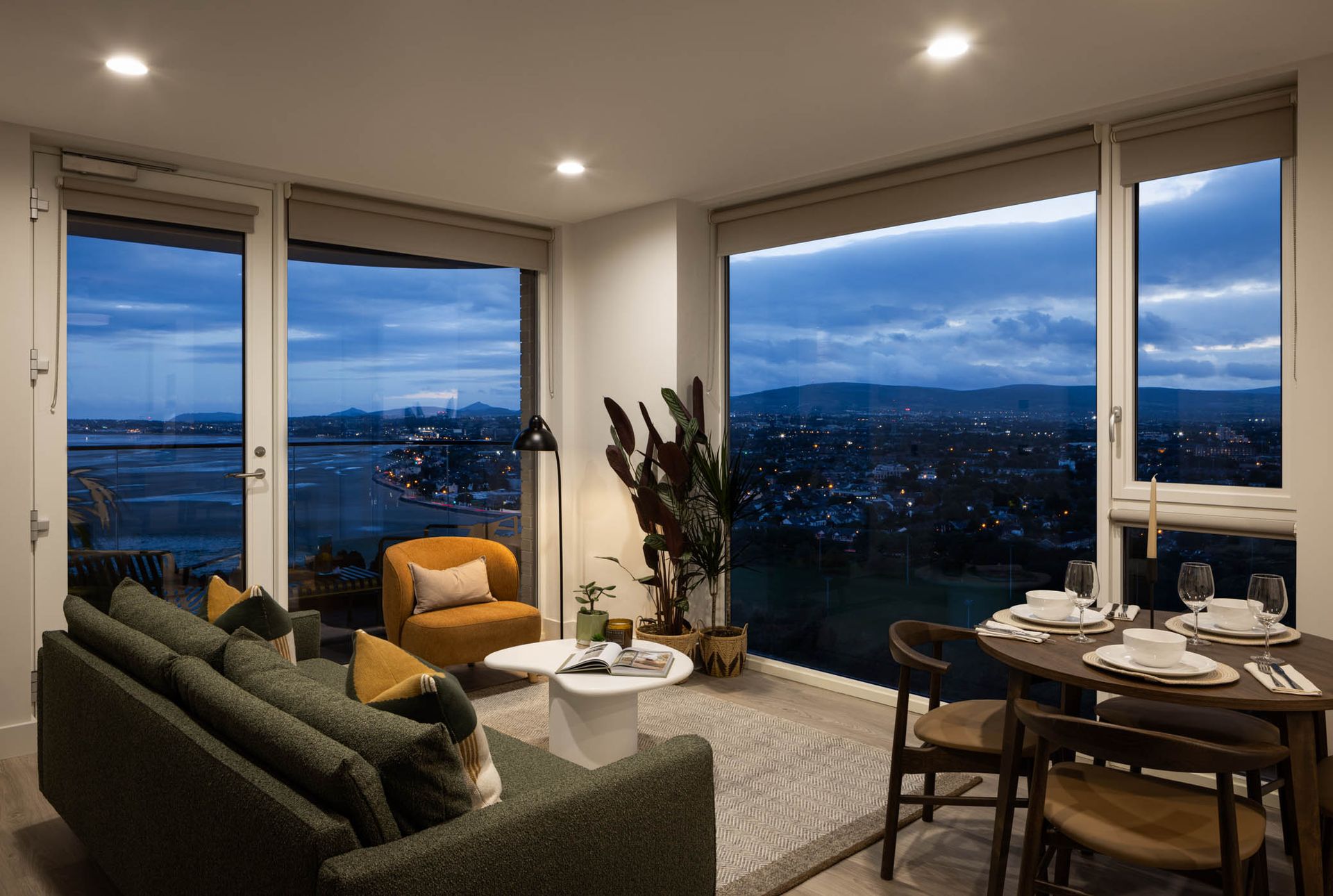 Modern living room with floor-to-ceiling windows and city view at dusk