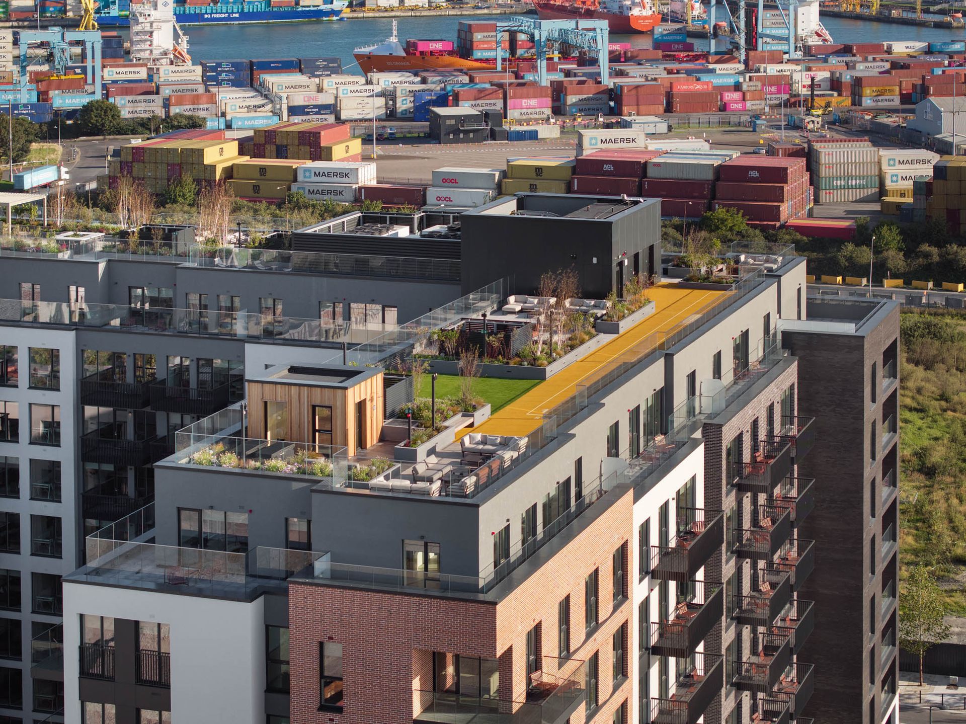 Modern apartment rooftop with yellow terrace overlooking a colorful shipping port