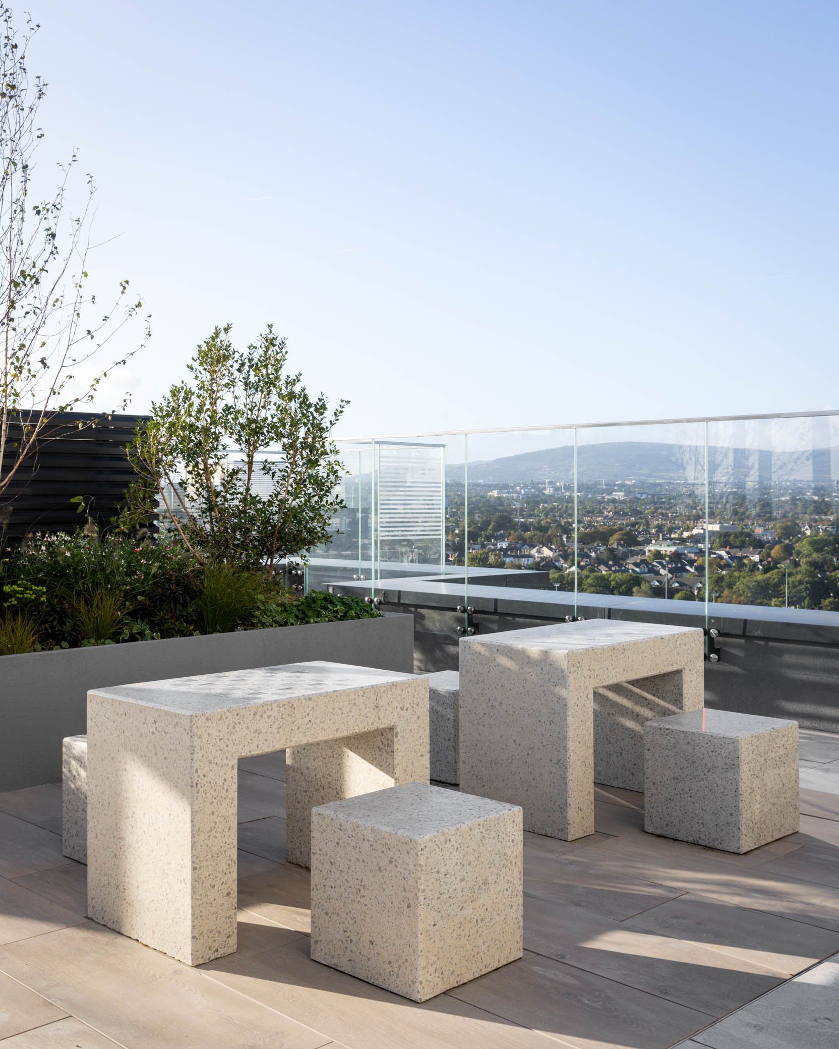 Stone outdoor seating on a rooftop terrace with city and hills in the background