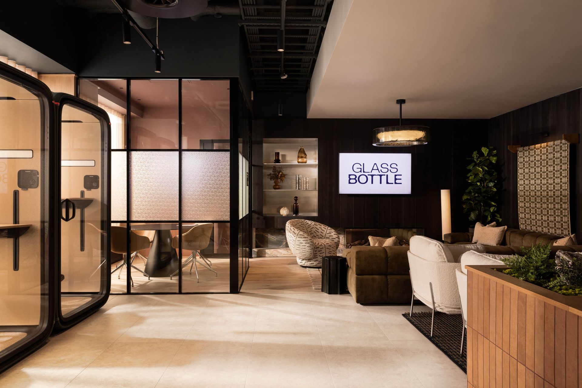 Modern café lounge with black-framed glass doors, sofas, warm lighting, and a coffee shop sign