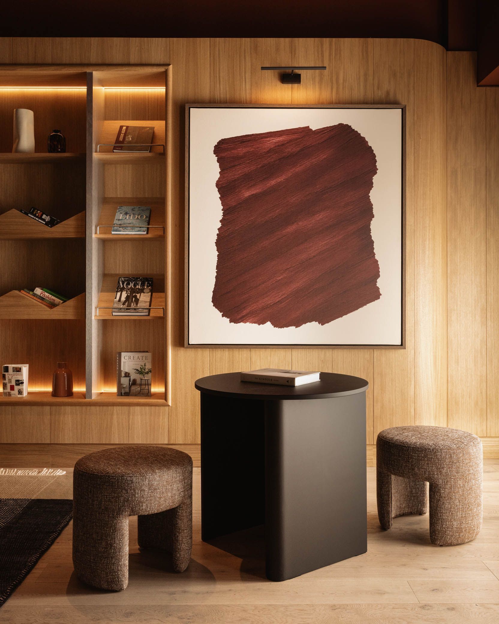 Modern living room with wood paneling, abstract wall art, woven stools, and a black pedestal table