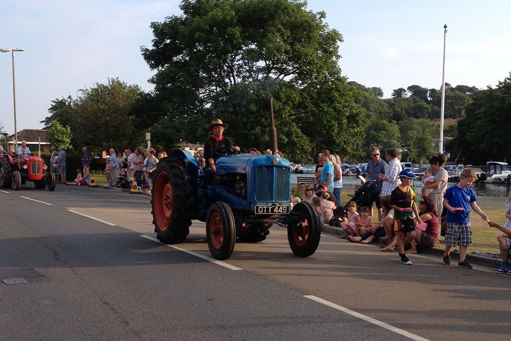 A man is driving a blue tractor down a street.