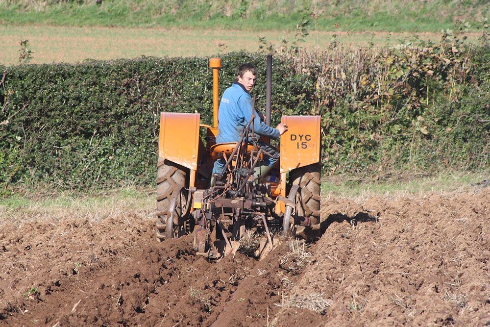 A man is plowing a field with an ayc tractor