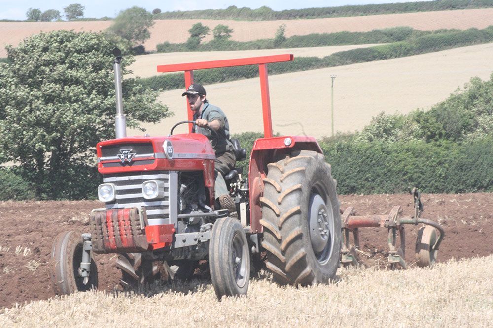 A man is driving a red tractor in a field