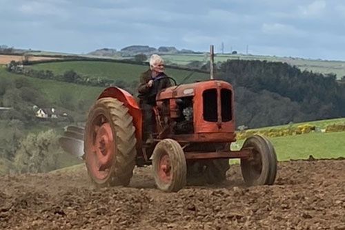 A man is driving an old red tractor through a field.