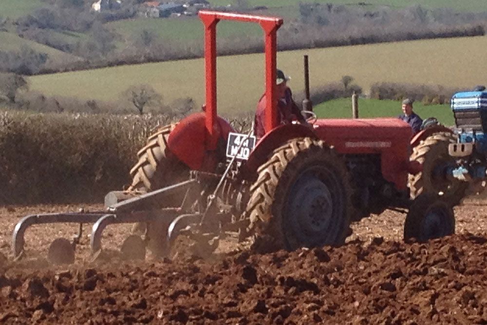 A man is driving a red tractor in a field