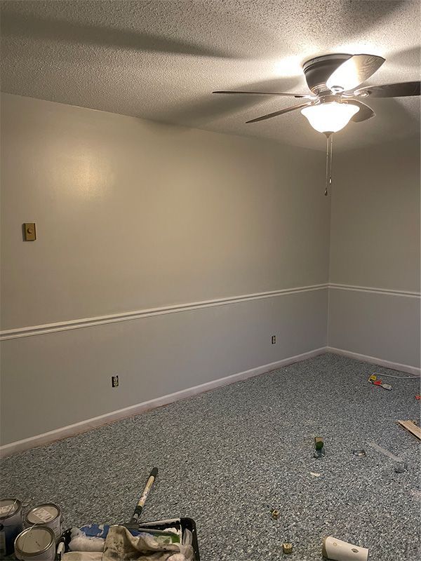 Empty room with gray walls, white trim, and blue patterned carpet. 