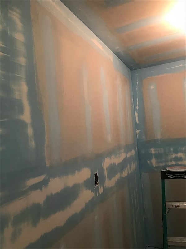 Interior view of a room with drywall, taped seams, and primer applied. 
