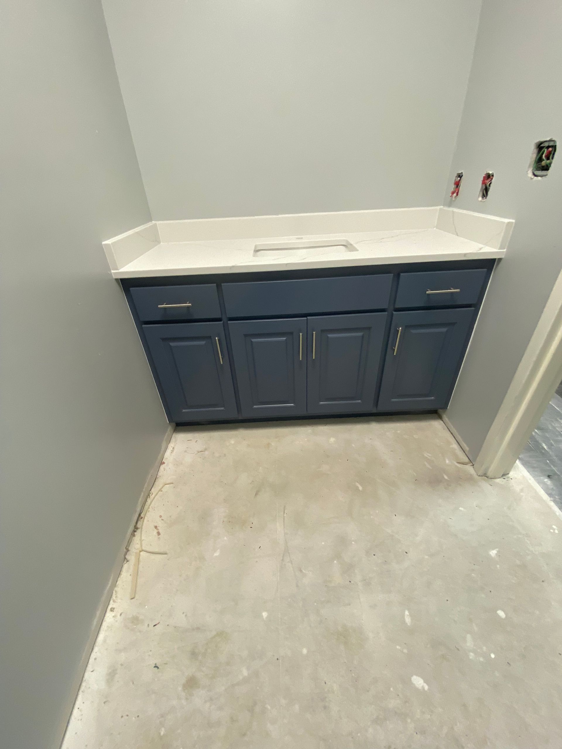 Empty bathroom with blue vanity and white sink countertop in a small gray-painted room.