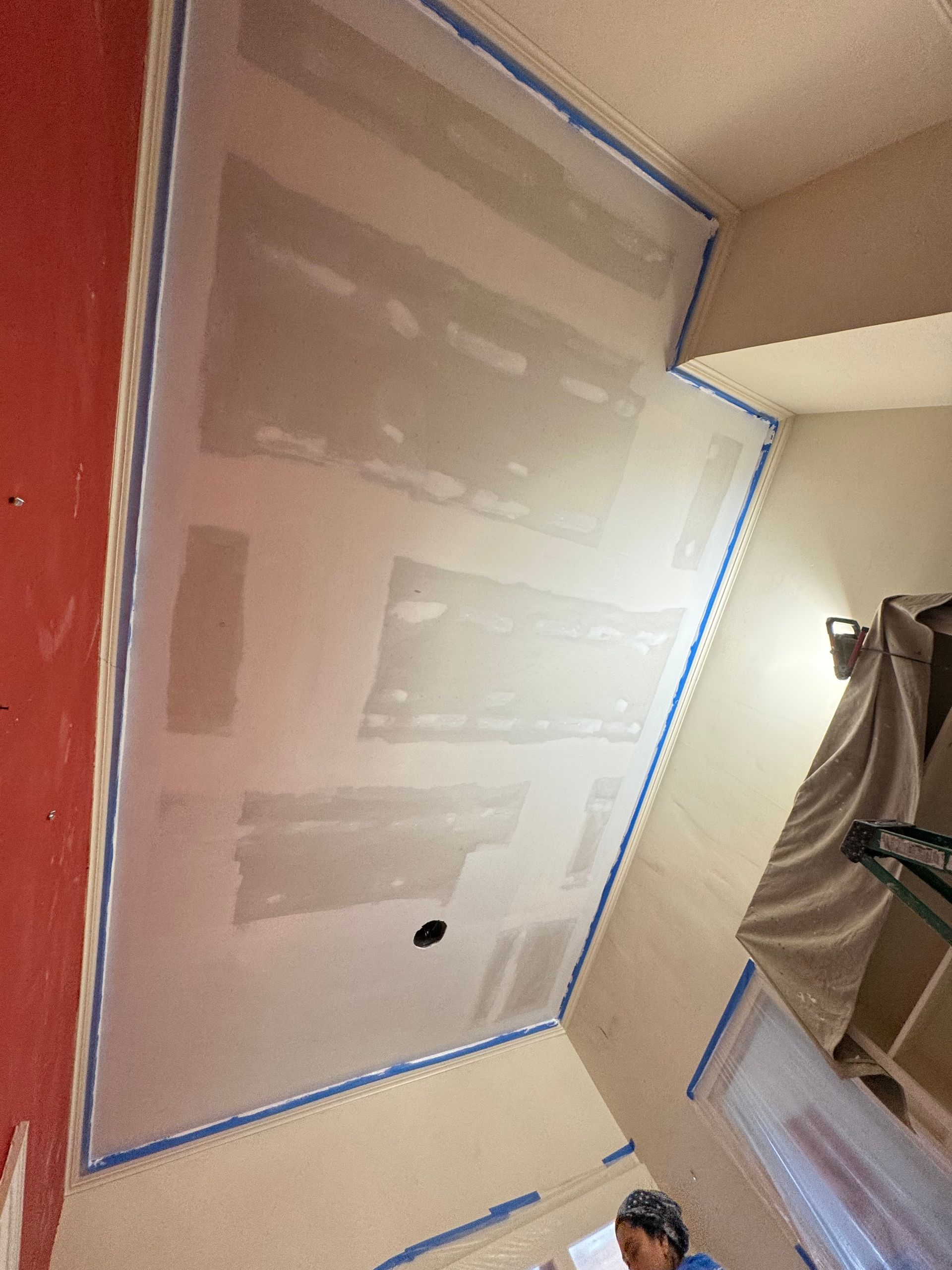 Painter’s tape outlining drywall patches on a wall under renovation
