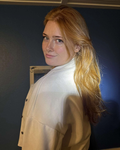 a woman with long blonde hair is smiling for the camera .