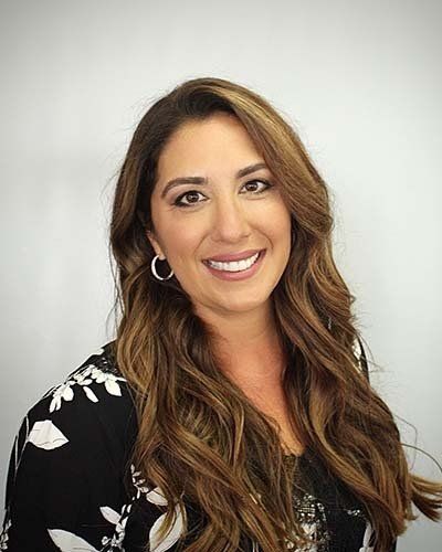 a woman with long hair and hoop earrings is smiling for the camera .