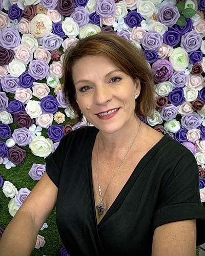 a woman is sitting in front of a wall of flowers .