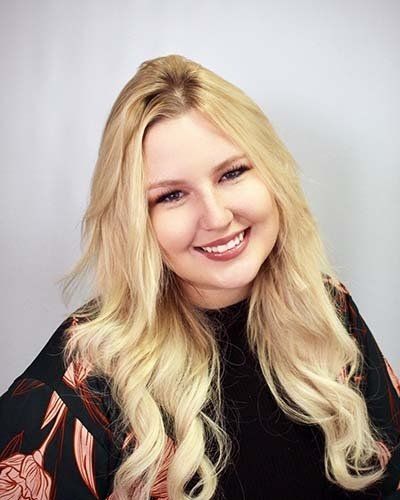 a woman with long blonde hair is smiling for the camera .