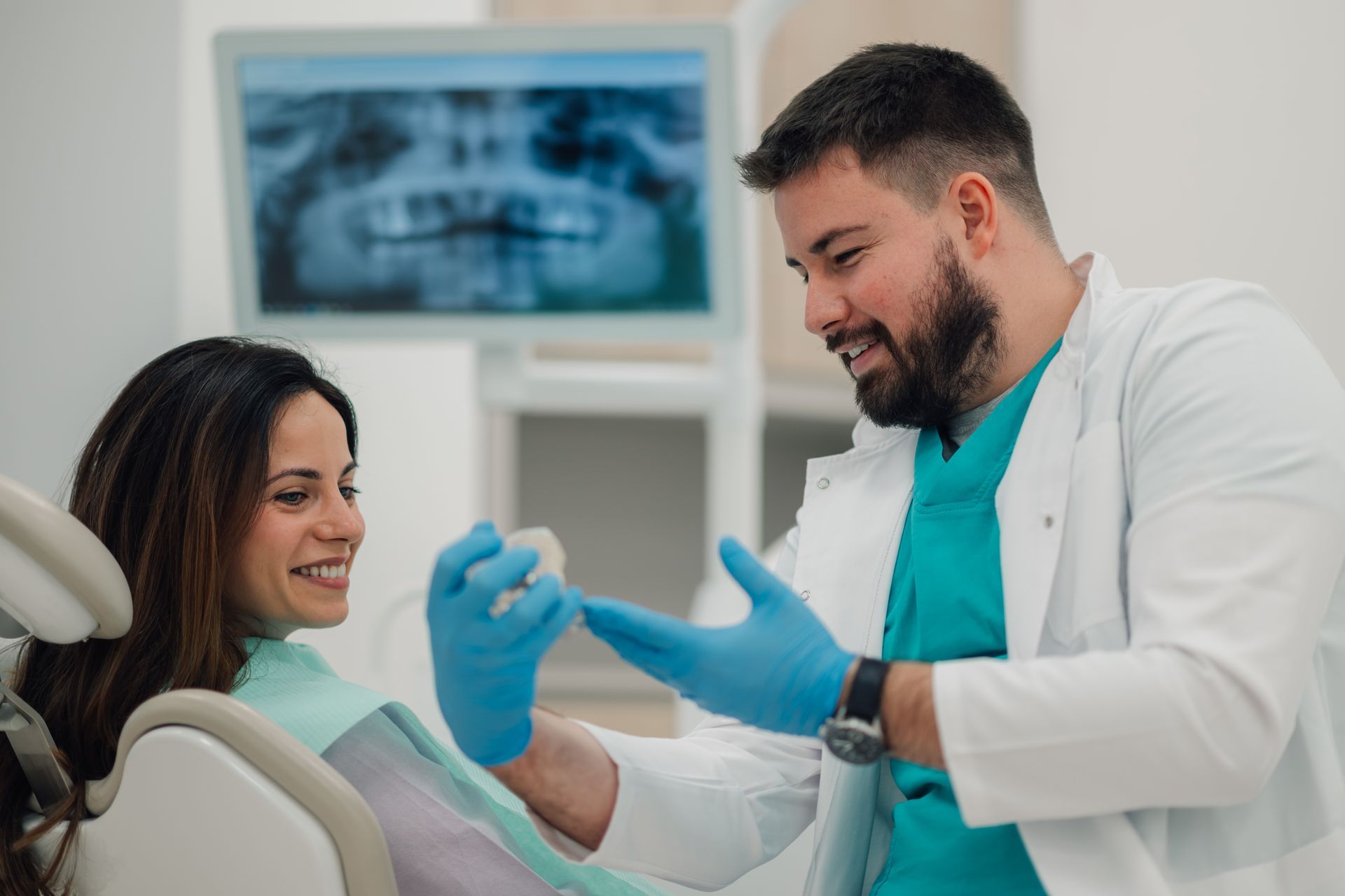 Dentist showing teeth model to patient in modern clinic.