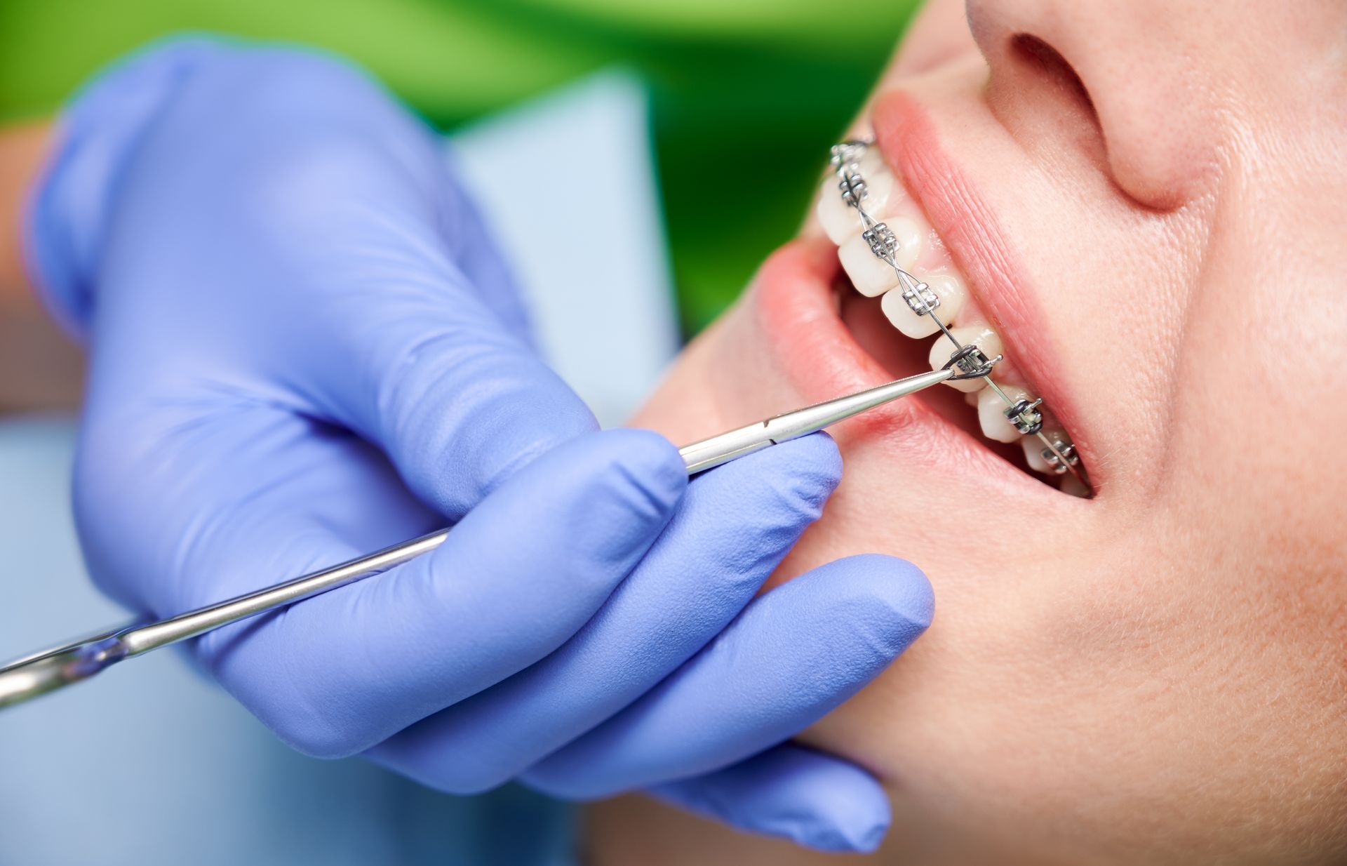 An orthodontist is adjusting a patient’s braces.